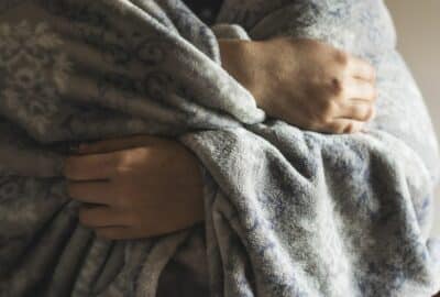 An elderly person with a blanket around their shoulders