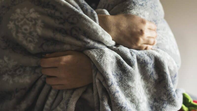 An elderly person with a blanket around their shoulders