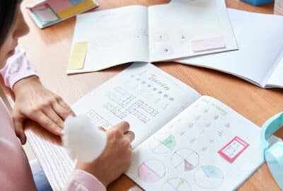 A young person sat studying with her study books out, at her desk