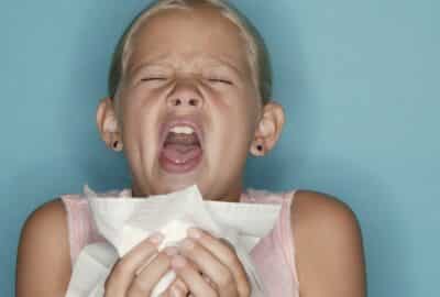 A child sneezing into a tissue