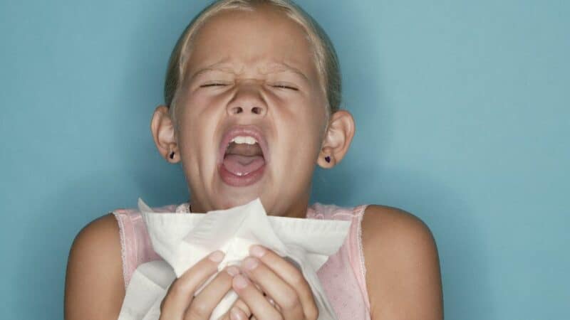 A child sneezing into a tissue