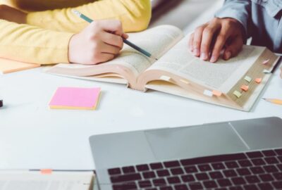 A teacher working with a pupil, both looking at a text book.