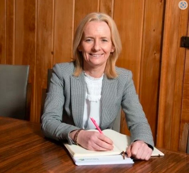 Donna Manson sat at a desk signing a document