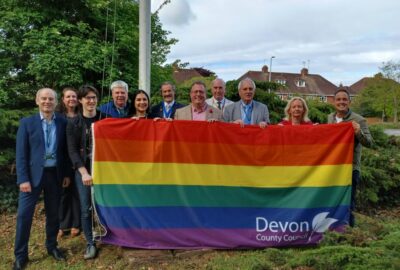 A group of people stood outside County Hall, holding the Pride flag between them, before it is raised.