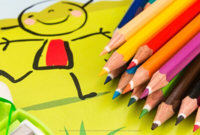 A child's stick-drawing of a child and different coloured colouring pencils