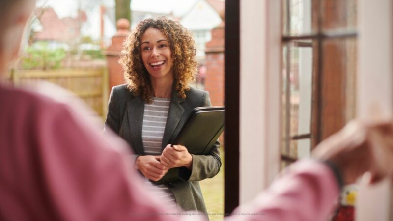 A social worker talking to a young person at the door of their house