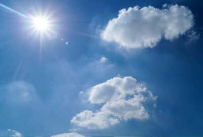 Blue sky with a bright sun and a few clouds