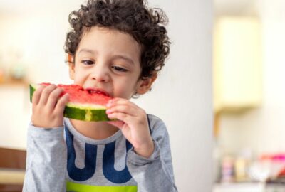 Young boy eating a water melon slice