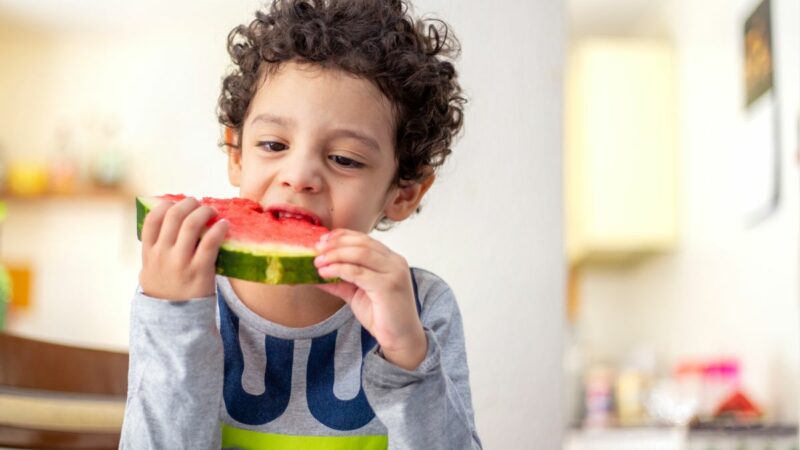 Young boy eating a water melon slice