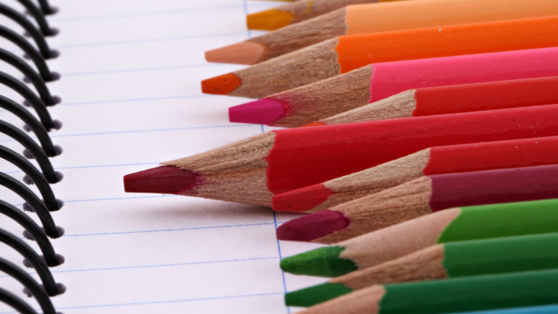 A set of colourful pencils on a page of lined paper