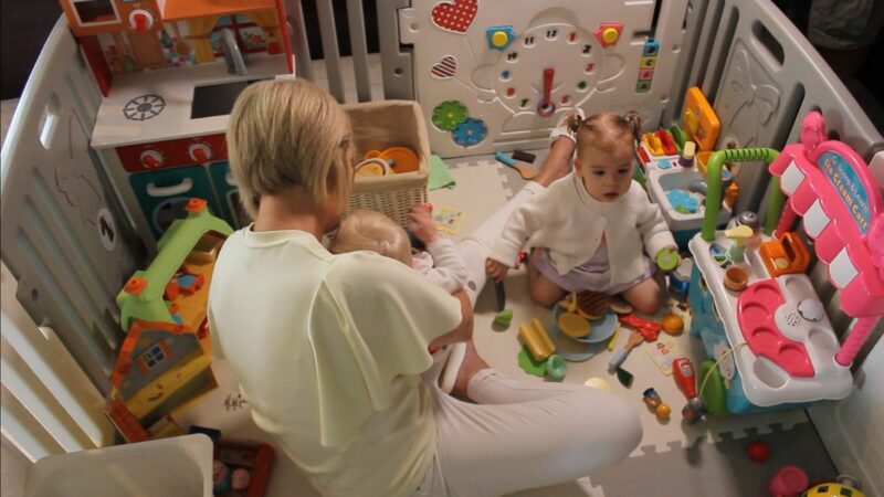 Hub carer, Sarah Whitby, playing with a young child in a baby's play pen.