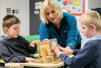 A staff member working with two young children, with an activity.