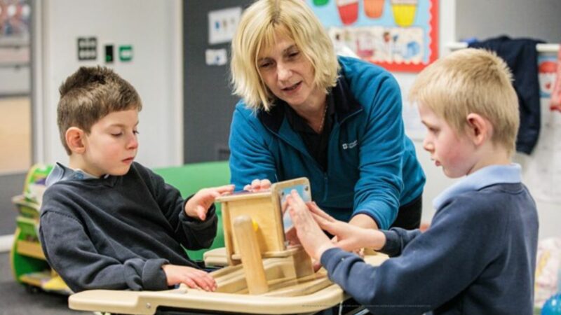 A staff member working with two young children, with an activity.
