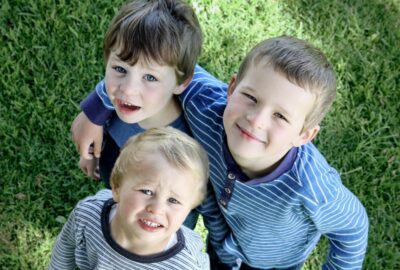 Three young children looking and smiling up at the camera