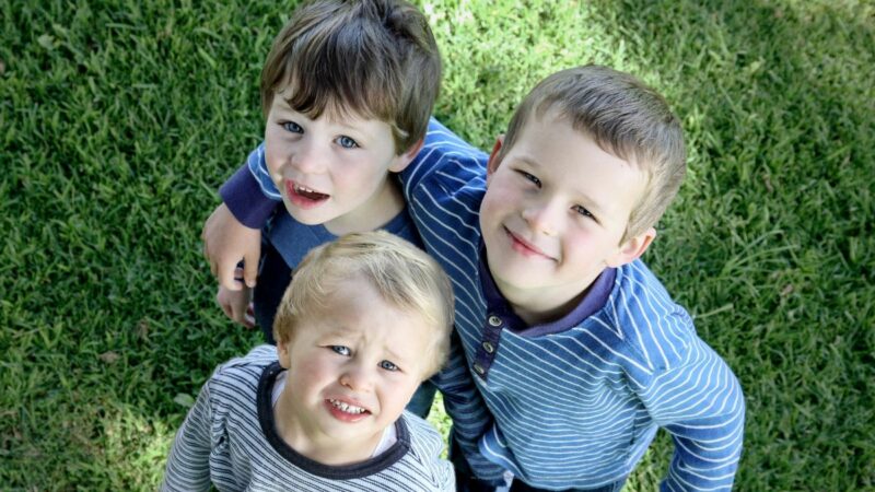 Three young children looking and smiling up at the camera