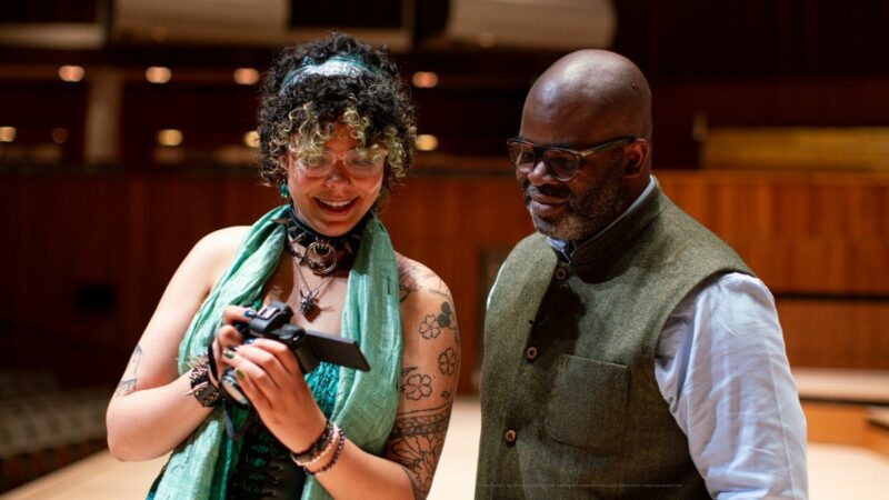 Amecia and Misan Harriman. Amecia is showing Misan a photo that she has taken on her camera