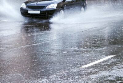 A car driving through rain with water spraying from the tyres