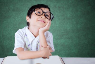 A young boy at school looking upwards as if day dreaming