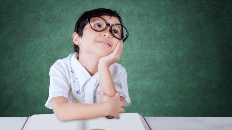 A young boy at school looking upwards as if day dreaming