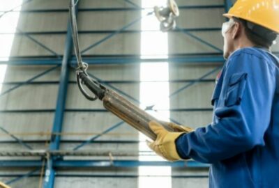 A worker in blue overalls and hard hat working in a factory