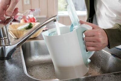 A person filling the kettle with water from the tap in a kitchen