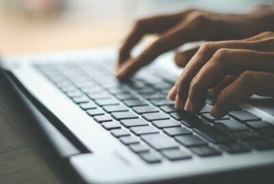 A person typing on a laptop. Only their hands are visible, on the keyboard of the laptop