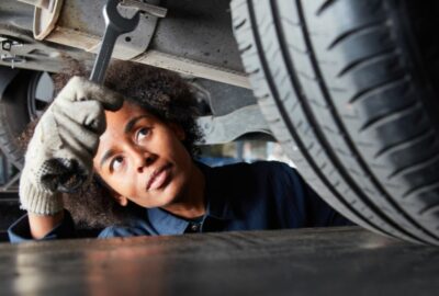 A young apprentice working as a mechanic in a garage. Picture shows the apprentice working under a car