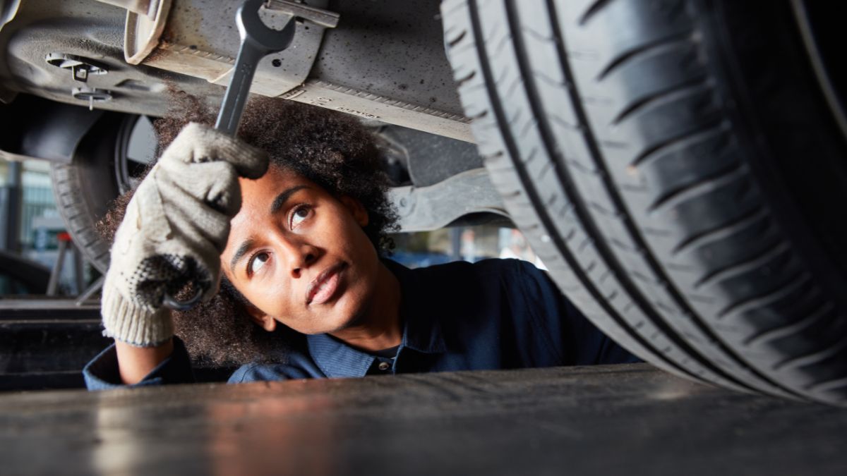 A young apprentice working as a mechanic in a garage. Picture shows the apprentice working under a car