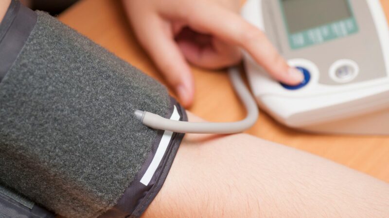 A person checking their own blood pressure using a monitor