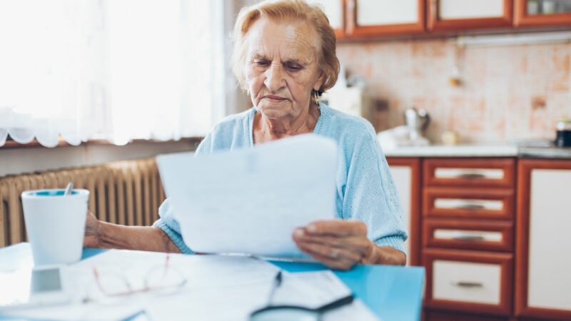A pensioner sat at her table at home looking at a bill