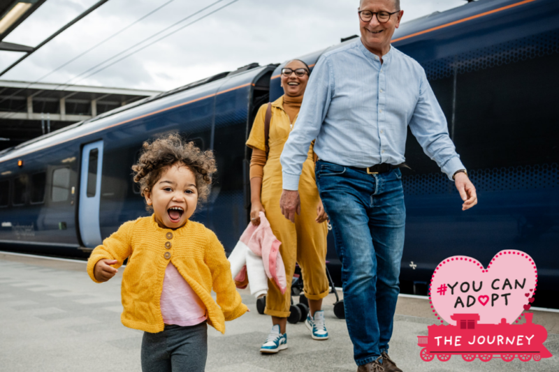 Foster carers and a child walking along a train station platform