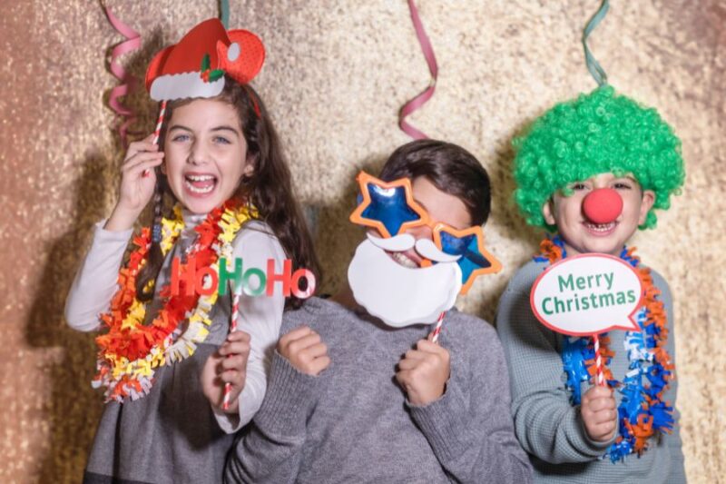 Children dressed in festive clothing holding signs saying Happy Christmas