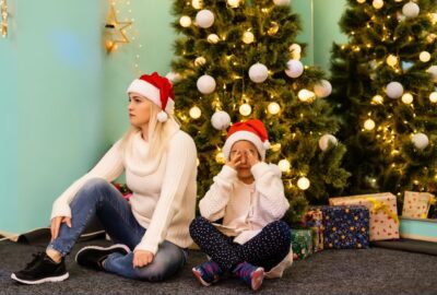 Mother and child sat under Christmas tree looking stressed