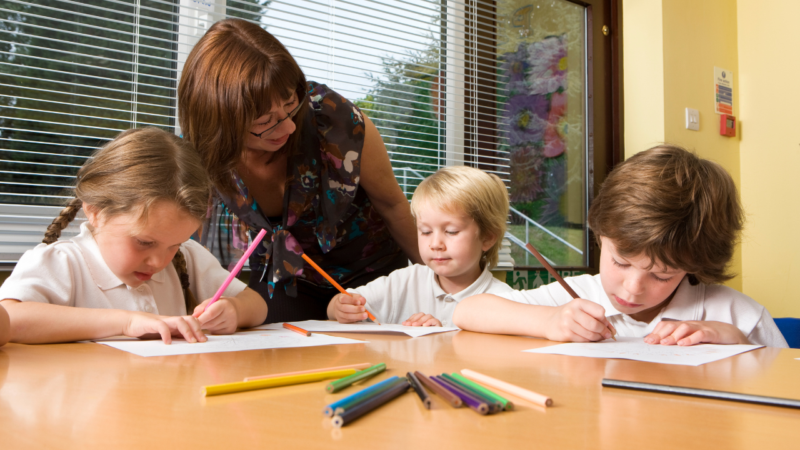 Children in a small group writing with a teacher