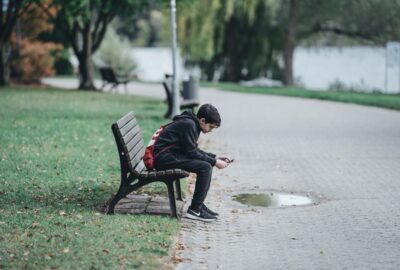 Teenage boy sat on a bench looking at phone