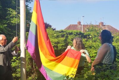 The Chairman of the Council, Cllr John Hart helping to raise the LGBTQ+ flag at County Hall, Exeter.