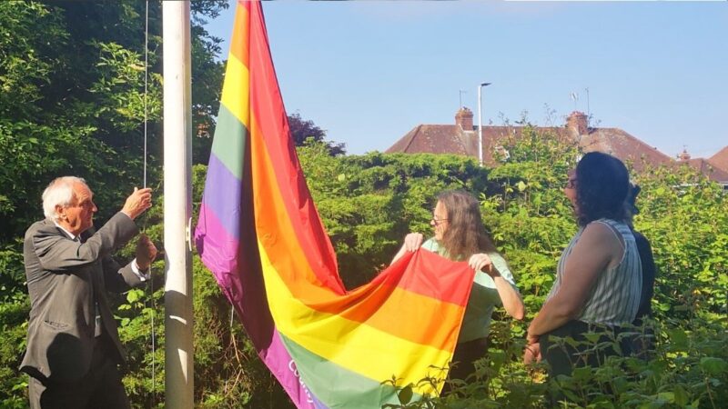 The Chairman of the Council, Cllr John Hart helping to raise the LGBTQ+ flag at County Hall, Exeter.