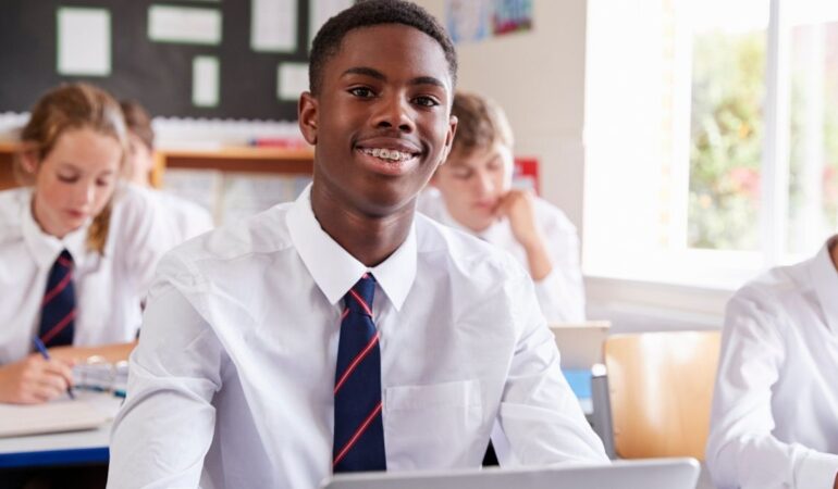 Teenagers in their classroom, sat at their desks looking towards the front of the class.