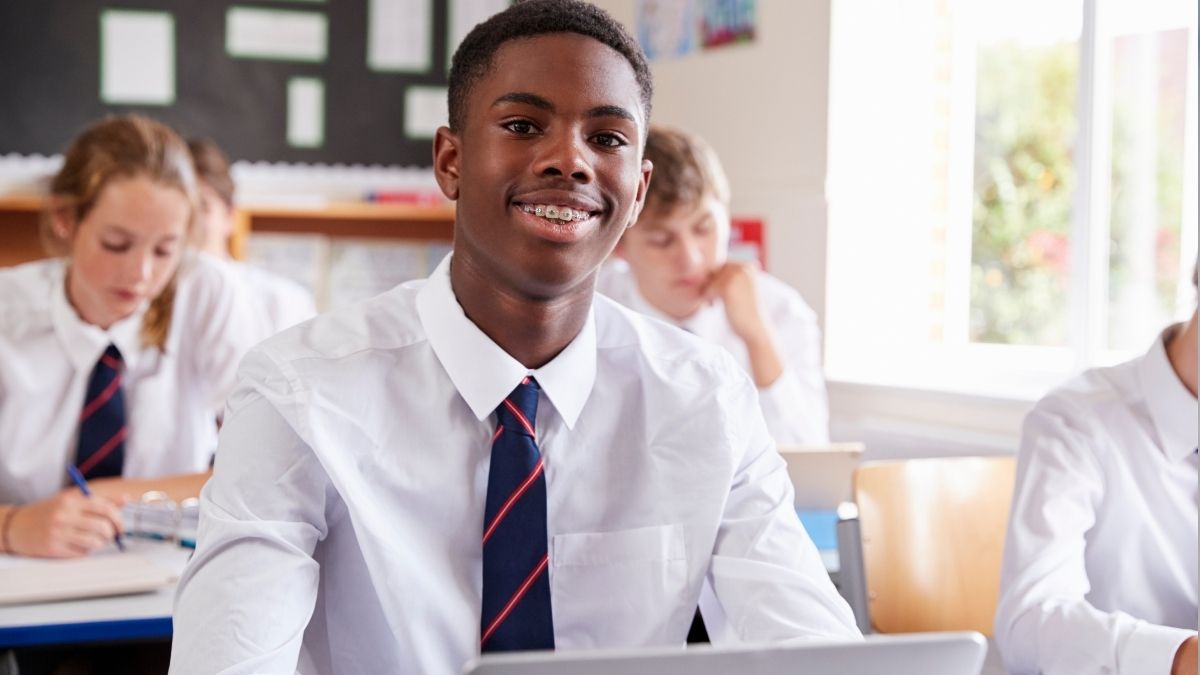 Teenagers in their classroom, sat at their desks looking towards the front of the class.
