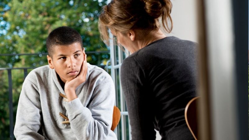 A teenager talking to an adult at home