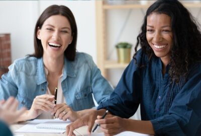 Two people at work in a meeting, smiling.