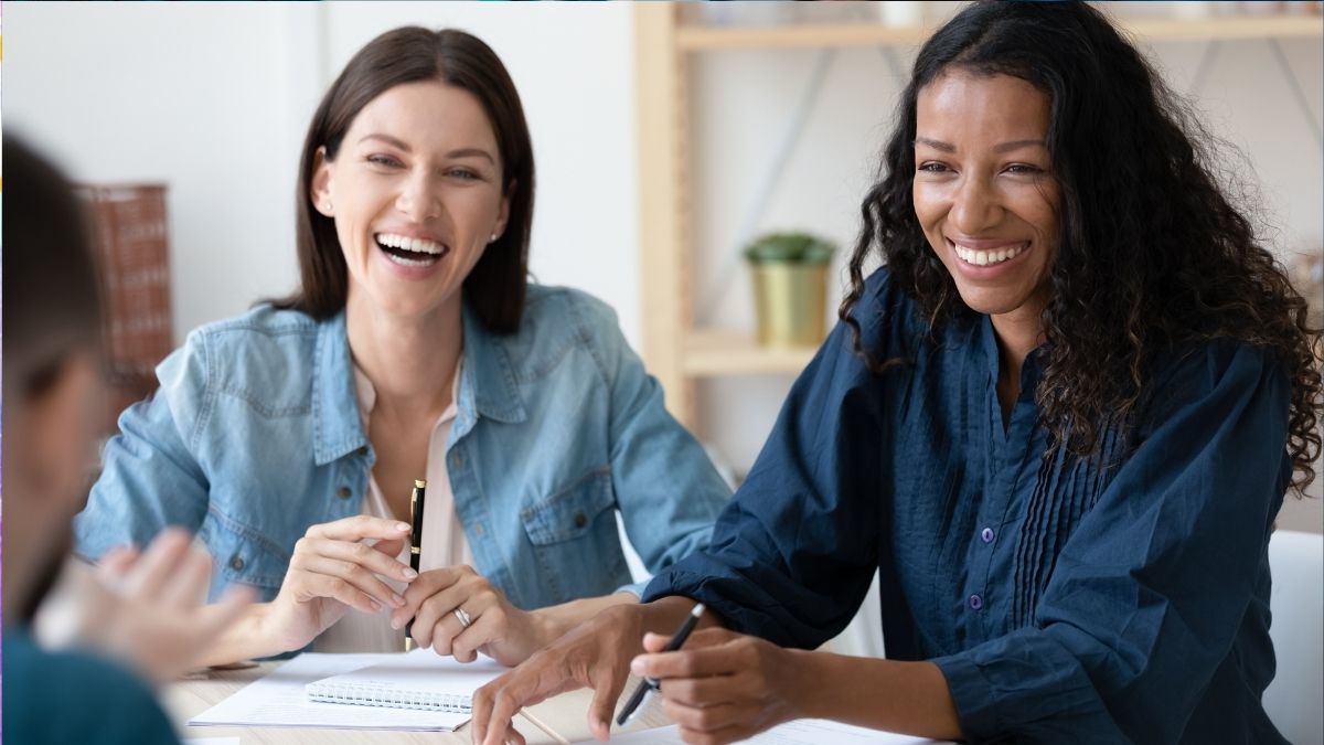 Two people at work in a meeting, smiling.