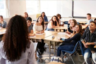 A class of teenagers at college. Tutor is talking at the front of the class
