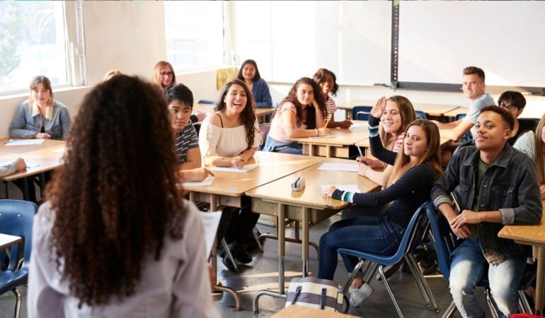 A class of teenagers at college. Tutor is talking at the front of the class