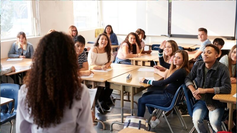 A class of teenagers at college. Tutor is talking at the front of the class