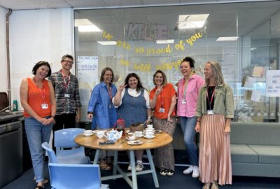 Khloe and the H2O team at Petroc College. The group are smiling and stood behind a desk with celebratory snacks