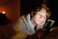 Teenage boy looking troubled, looking at his mobile phone/tablet/screen