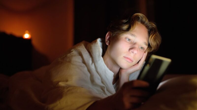 Teenage boy looking troubled, looking at his mobile phone/tablet/screen