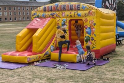 A bouncy castle in the grounds at County Hall, Exeter. Photo shows the backs of a foster carer and two unidentifiable young children