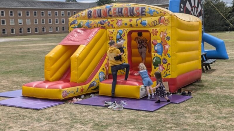 A bouncy castle in the grounds at County Hall, Exeter. Photo shows the backs of a foster carer and two unidentifiable young children